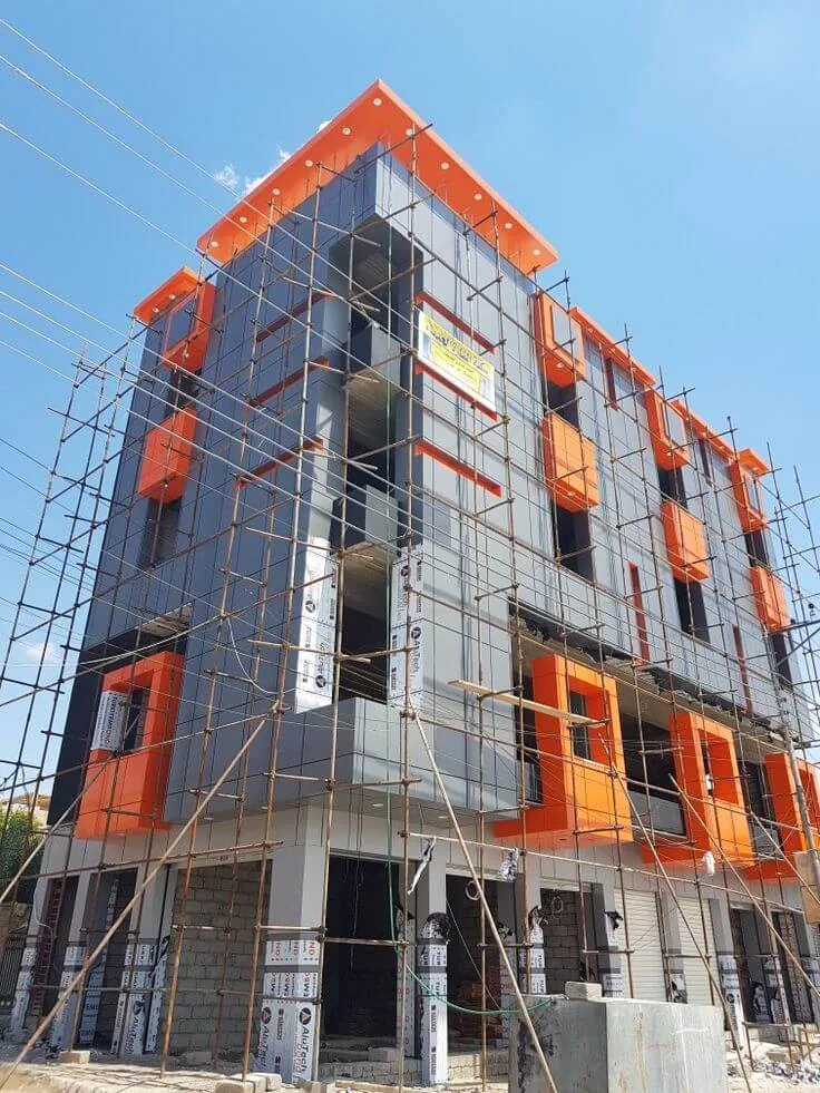 Composite panel cladding going up on a multi-storey frame under scaffold