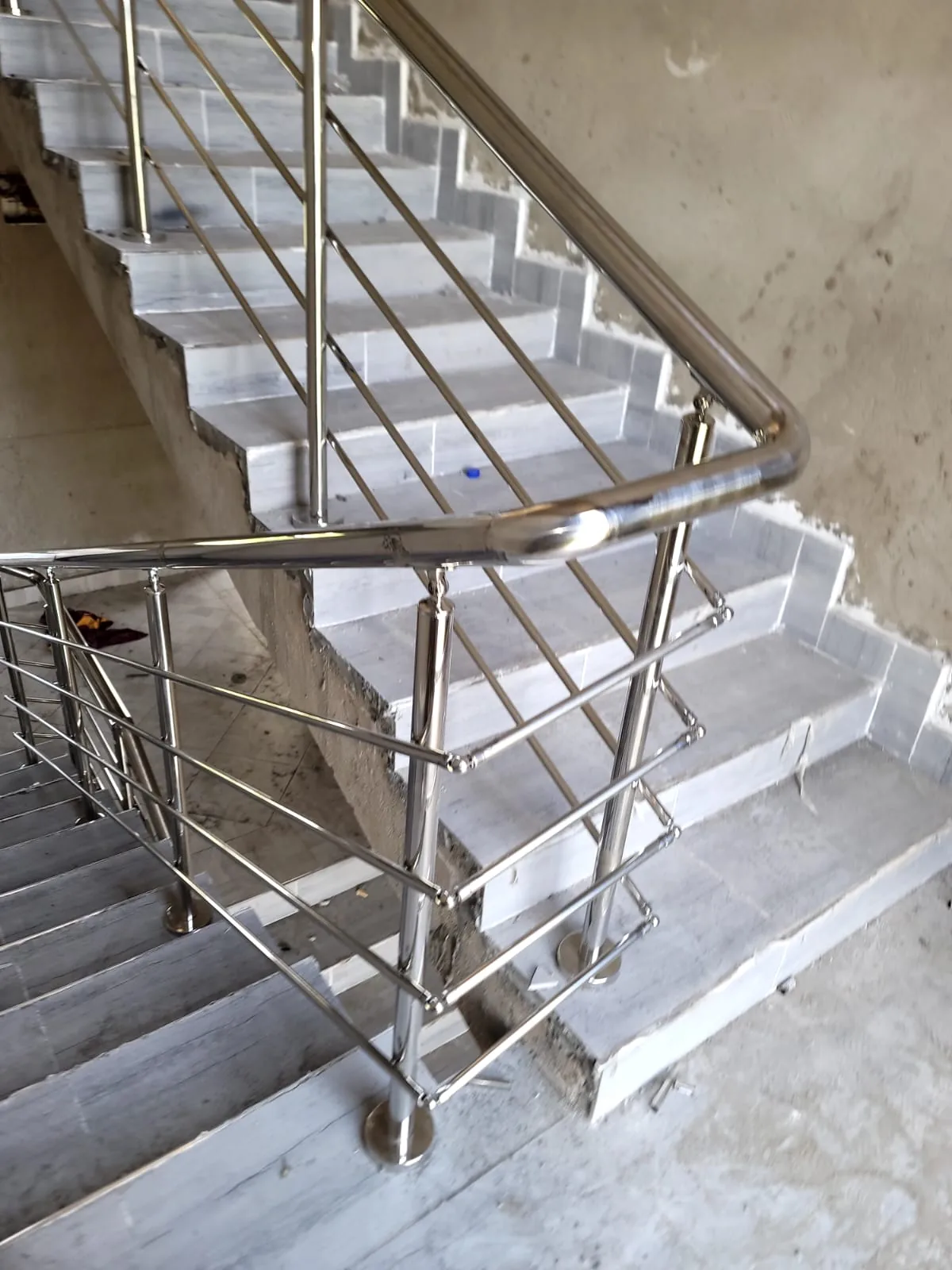 Stainless steel stair railing with horizontal infill bars over a concrete flight