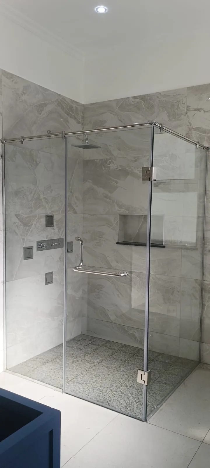 Frameless corner shower enclosure in a tiled Nairobi bathroom